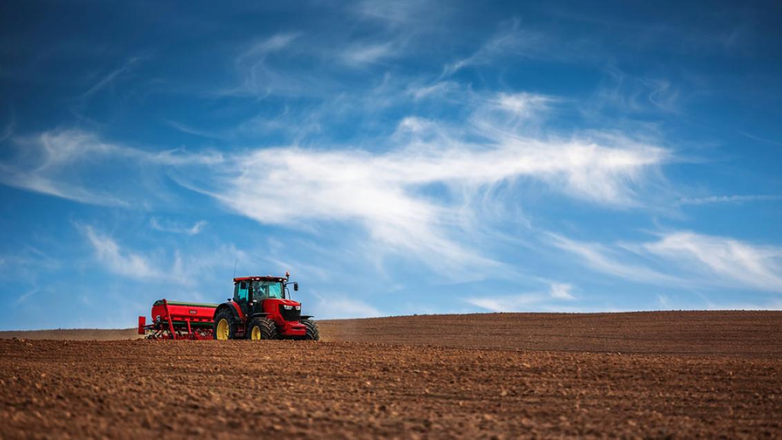 red tractor plowing dirt 