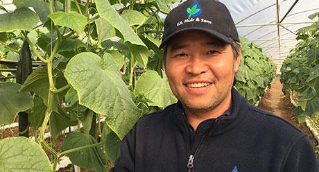 Tommy Le standing next to crop