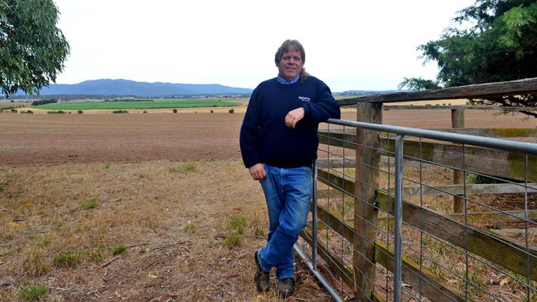 man leaning on fence grinning 