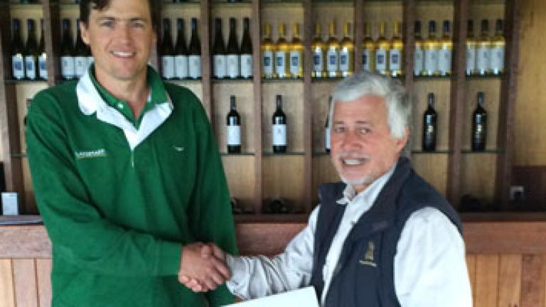 two men shaking hands in front of wine display