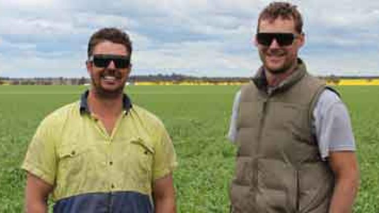 two men with sunglasses standing in a field 