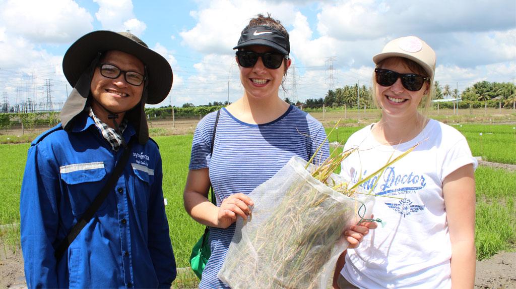 three people, one holding a bag of wheats 